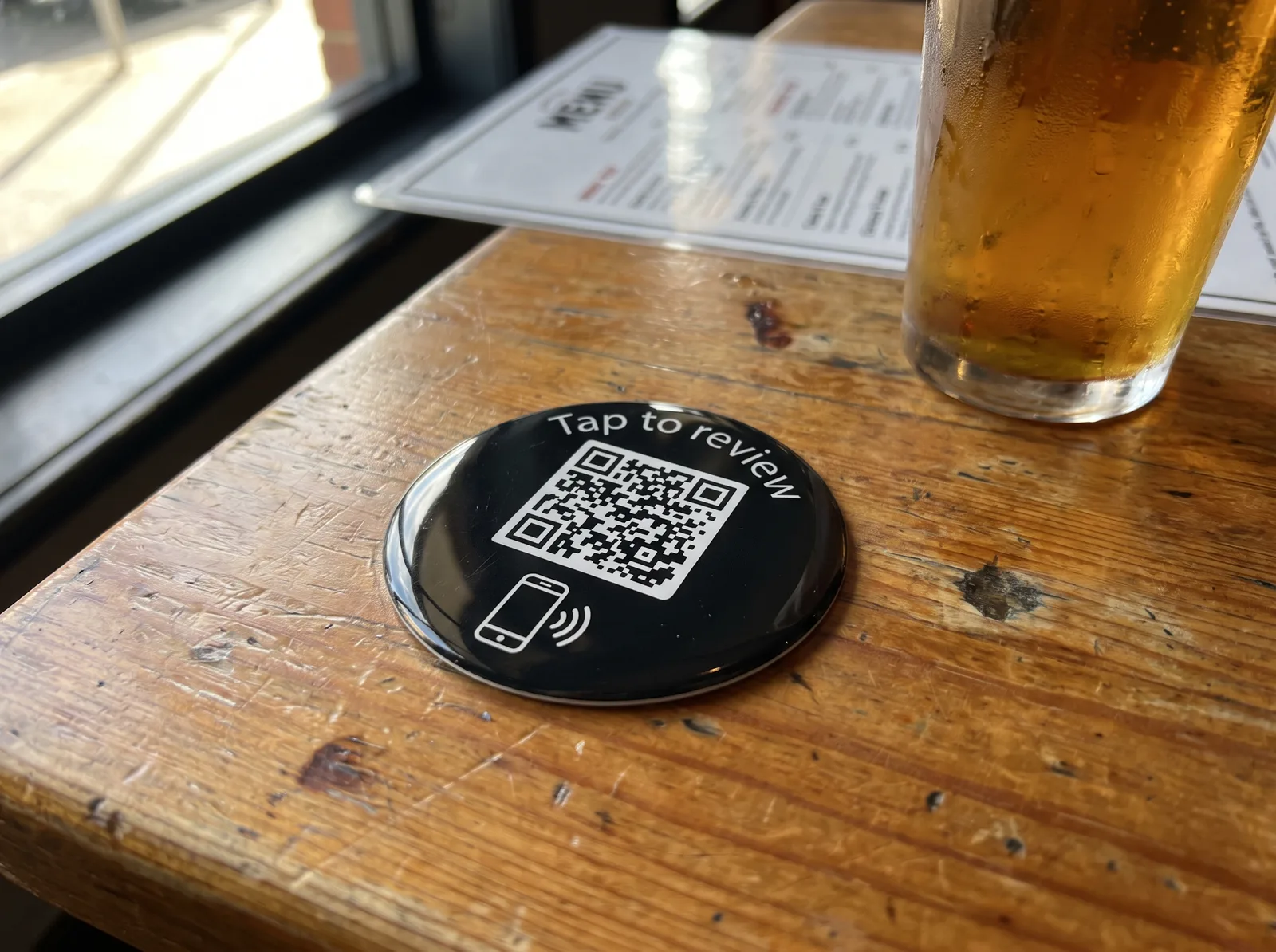 Round tap-to-review sticker on a pub table
